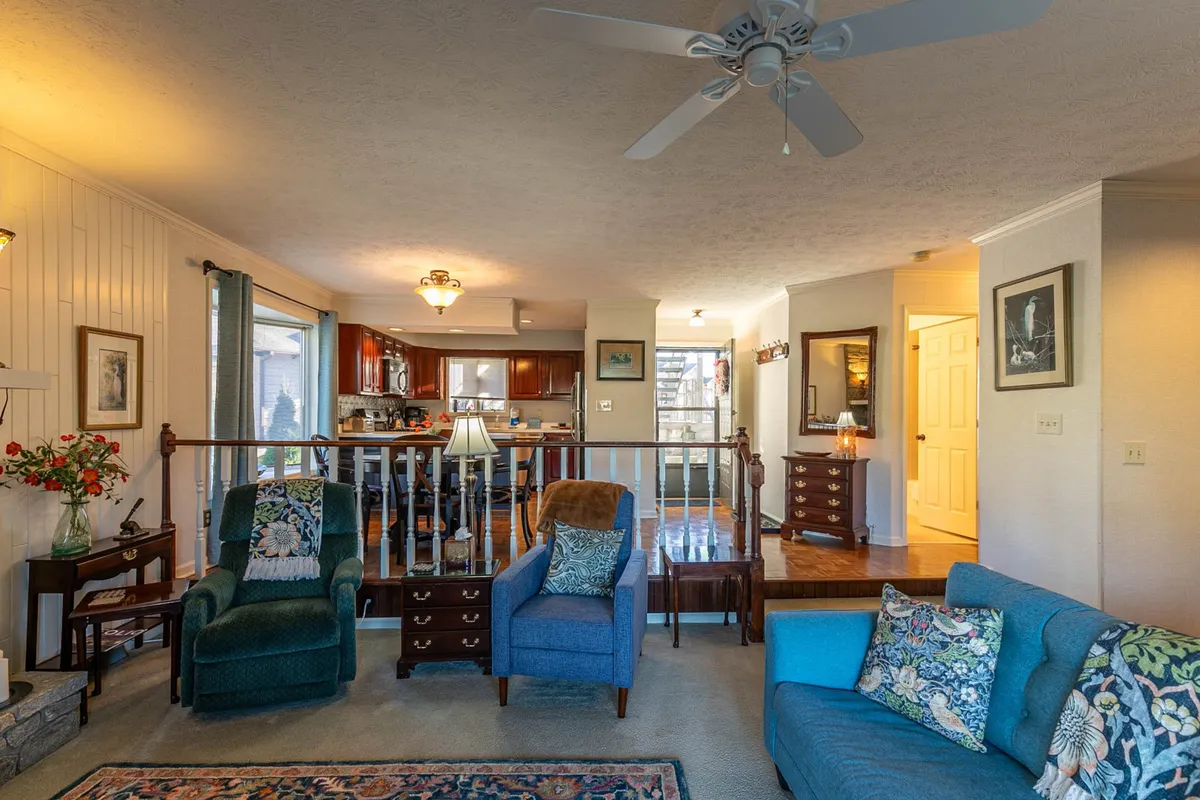 A welcoming living area with a comfortable seating arrangement and a decorative rug, partially revealing the kitchen. The cozy space is ideal for relaxing, reading, or socializing, and can readily accommodate a sleeper sofa for additional guests.