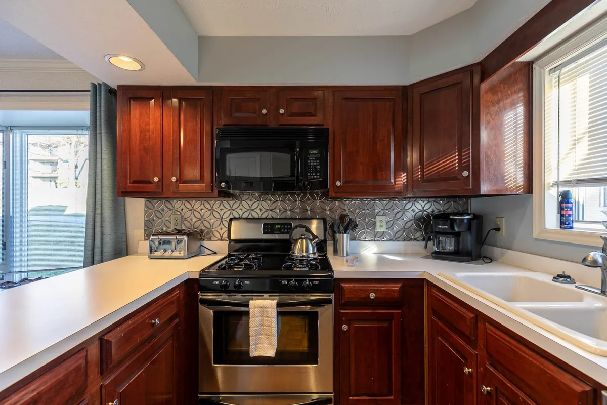 This interior shot focuses on a modern kitchen with stainless steel appliances, wooden cabinetry, attractive countertops, and a kitchen sink. The space is well-lit and suggests a practical, thoughtfully stocked area ideal for preparing hearty breakfasts or elegant dinners.