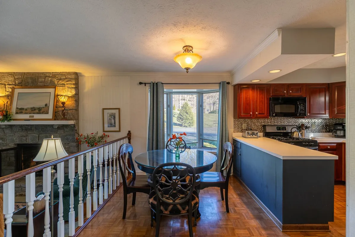 A cozy dining area highlighted by a welcoming fireplace and a window view, suggesting a warm, restful atmosphere. The space is suitable for gathering, reading, or enjoying quiet meals, with natural light and mountain ambiance filtering in from outside.